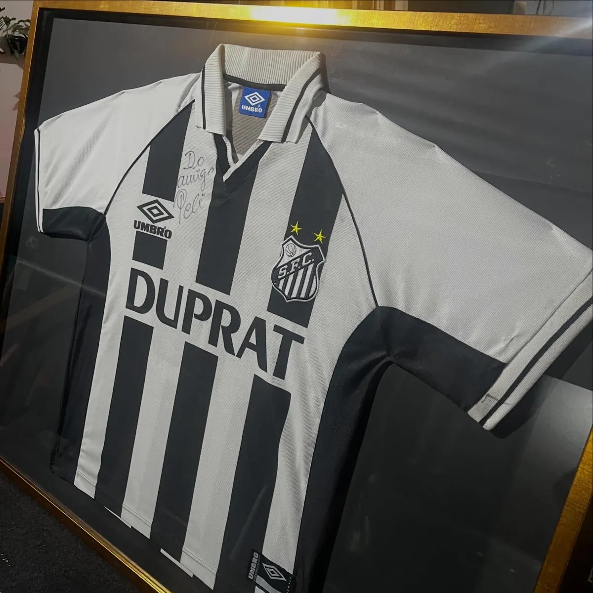 Camisa do Santos autografada pelo Pelé emoldurada com fundo preto e moldura dourada