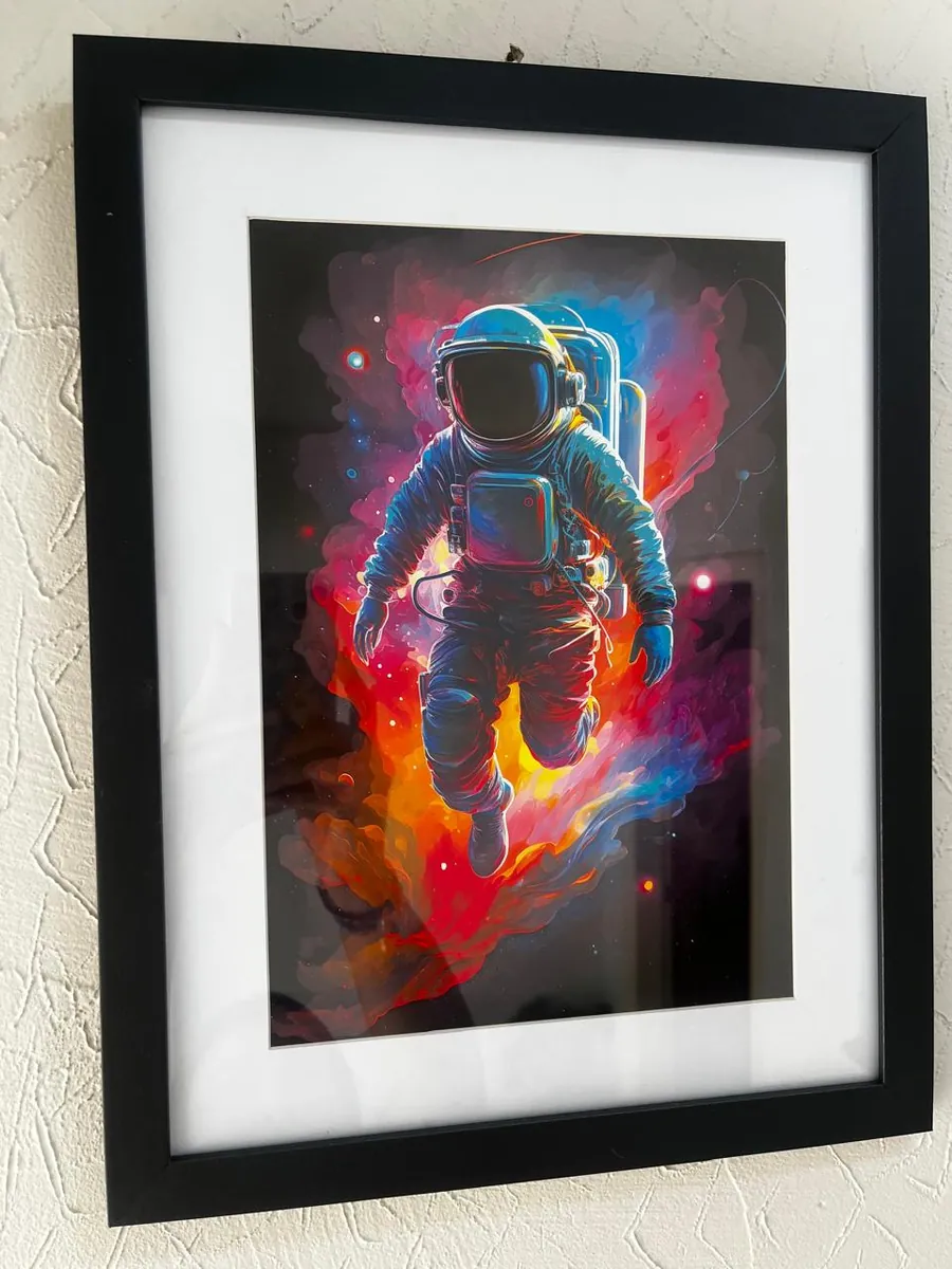 Quadro com impressão colorida de astronauta, paspatur branco e moldura preta