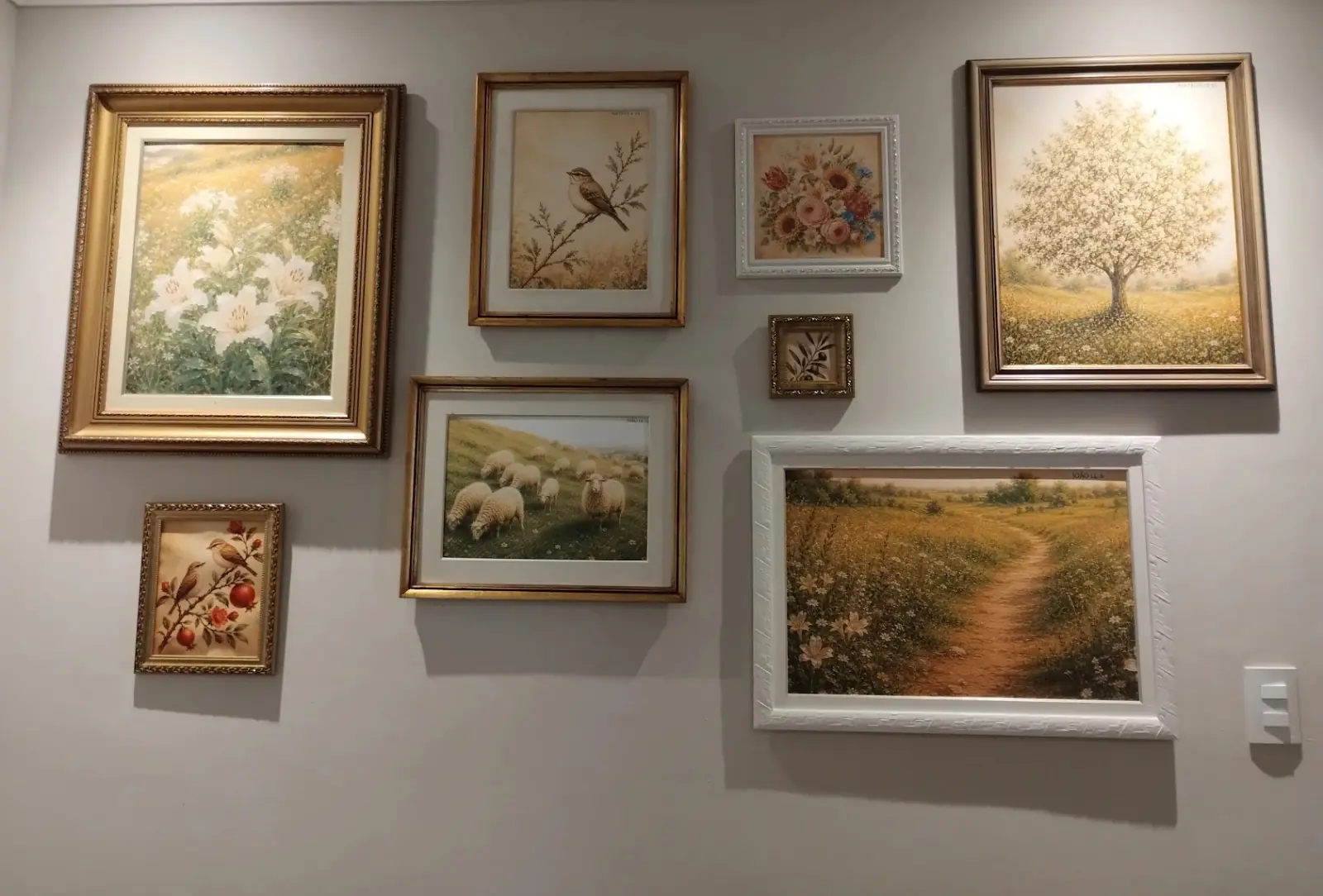 Parede com quadros de pinturas em molduras douradas e brancas feitas sob medida
